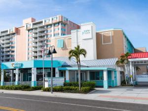 a building on a street with palm trees in front of it at Dolphin Sands Clearwater Beach, an Ascend Collection Hotel in Clearwater Beach
