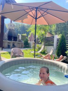 a young child in a hot tub with an umbrella at Vila Mama Jana in Buşteni