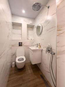 a white bathroom with a toilet and a sink at Guestrooms Zoya in Chernomorets