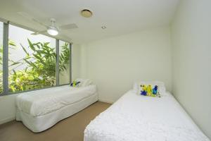two beds in a white room with a window at Blue on Blue Apartment 912 in Nelly Bay