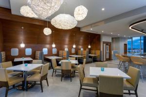 a restaurant with tables and chairs and chandeliers at Wyndham Garden Miami International Airport in Miami