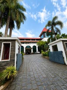 a house with palm trees in front of a driveway at Hotel Xavier's Avenue in Kadavoor