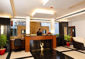 a man standing at a bar in a lobby at Hotel Xavier's Avenue in Kadavoor