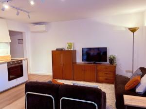 a living room with a couch and a tv on a cabinet at Verblijf in het Pajottenland in Gooik