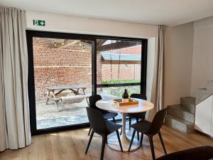 a dining room with a table and chairs and a large window at Verblijf in het Pajottenland in Gooik +21 photos