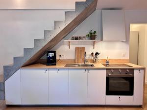 a kitchen with white cabinets and a staircase at Verblijf in het Pajottenland in Gooik