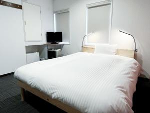 a bedroom with a white bed and a television at CHALET BURLAP FURANUI in Furano