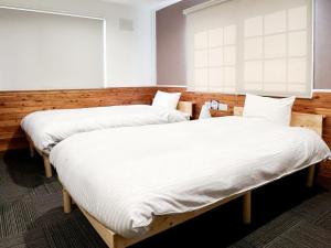 two beds in a room with white sheets at CHALET BURLAP FURANUI in Furano