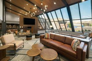 a living room with a couch and tables and windows at Four Points by Sheraton Rock Springs in Rock Springs