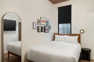 a white bedroom with a bed and a mirror at FOUND Hotels, Chicago, Series by Marriott in Chicago