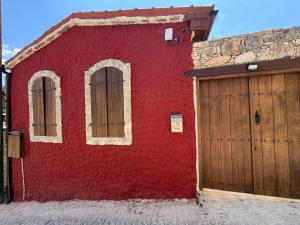 a red building with a door and a garage at Melograno Lofou in Lofou