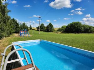 a swimming pool next to a field with a playground at Domki u Karola Domek nr 1 in Mikołajki