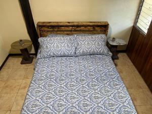 a bed with a blue and white comforter and a pillow at Rincón del río B&B in Ángeles