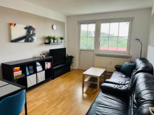 a living room with a leather couch and a table at FeWo Einetal 3 im schönen Ostharz in Harzgerode