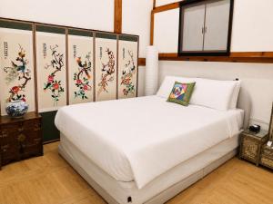 a white bed in a room with paintings on the walls at HAEMIL Hanok 해밀한옥 in Seoul +54 photos