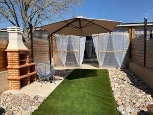 a patio with an umbrella and a chair and grass at Can Padrosa Mini loft 3 in Riumors