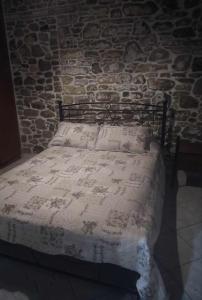 a bed in a room with a stone wall at Riverbird House in Kymi