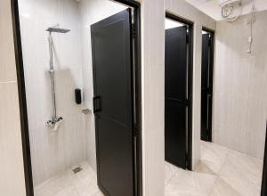 a bathroom with a shower and a black door at Wave Hostels Arugam Bay - With Swimming Pool in Arugam Bay