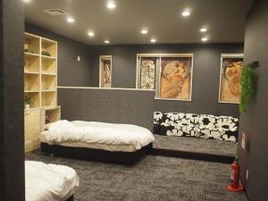 a room with two beds in it with pictures on the wall at ゲストハウスノーチェ in Shingū