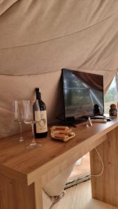 a table with a tv and a bottle of wine at Sutjeska Glamping Domes in Tjentište +11 photos
