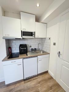 a kitchen with white cabinets and a sink and a microwave at Kents Hill Studio in Woolstone +16 photos