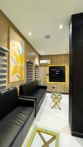 a living room with black leather couches and a flat screen tv at Ciamo Hotel in Ikeja