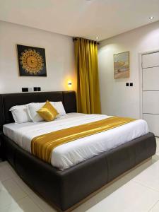 a bedroom with a large bed with yellow curtains at Ciamo Hotel in Ikeja