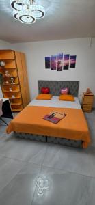 a bedroom with a large bed with an orange blanket at Maca apartman 23 in Petrovaradin