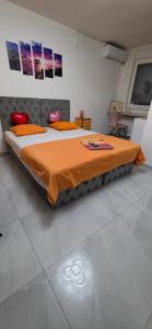 a bedroom with a large bed with an orange blanket at Maca apartman 23 in Petrovaradin