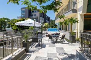 an outdoor patio with tables and chairs and an umbrella at Hotel Trezor in Varna City