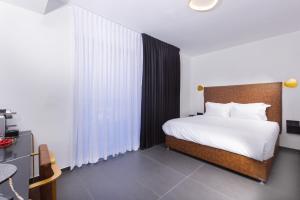 a bedroom with a bed with white sheets and white pillows at H34 Boutique Hotel & Spa by the sea of Nahariya in Nahariyya