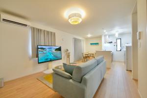 a living room with a couch and a television on a wall at 北谷町港2 in Chatan