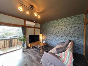 a living room with a couch and a tv at Kawazu Sakura-so in Kawazu