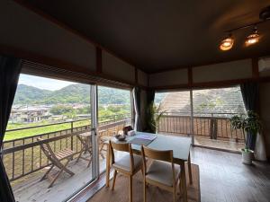 a dining room with a table and chairs and windows at Kawazu Sakura-so in Kawazu