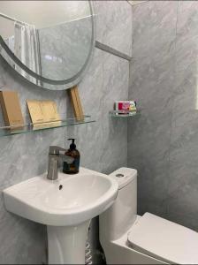 a bathroom with a sink and a toilet and a mirror at Mahika Guest House Siquijor in San Juan