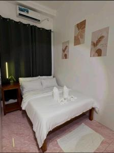 a bedroom with a bed with white sheets and towels at Mahika Guest House Siquijor in San Juan