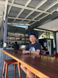 a man is sitting at a wooden table at Mahika Guest House Siquijor in San Juan