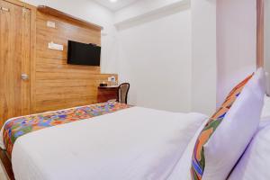 a bedroom with a bed and a tv on a wall at FabHotel Shaurya Inn MIDC in Ghansoli