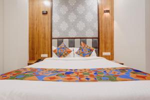 a bedroom with a white bed with colorful sheets and pillows at FabHotel Shaurya Inn MIDC in Ghansoli