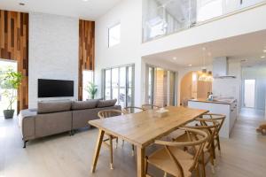 a kitchen and living room with a wooden table and chairs at RYOAN Ichinomiya in Ichinomiya