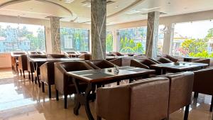 a dining room with tables and chairs and windows at Jowar Hotel & Resort in Digha