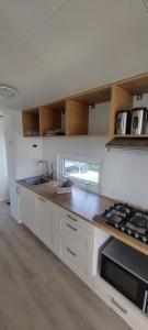 a kitchen with a sink and a stove top oven at Veluwemeer Lodge in Elburg +4 photos