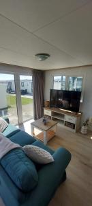 a living room with a blue couch and a flat screen tv at Veluwemeer Lodge in Elburg