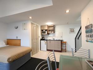 a small bedroom with a bed and a kitchen at Athena Motel in Christchurch