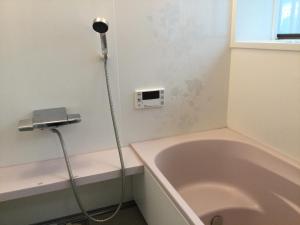 a bathroom with a bath tub next to a window at いちご荘 in Ichihara