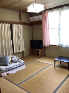 a living room with a bed and a tv at いちご荘 in Ichihara