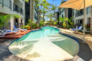 a swimming pool at a resort with chairs and an umbrella at Laguna Edge - Swim-Out Studio, near Sea & Dining in Trinity Beach