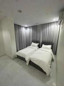 two beds with white sheets and pillows in a room at شقق تأجير يومي in Musaylah