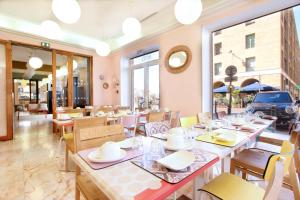 ein Esszimmer mit Tischen, Stühlen und Fenstern in der Unterkunft Hôtel Hermès in Marseille