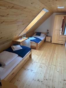 two beds in a room with wooden floors at Chalupa v prírode in Pliešovce